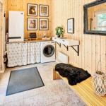 Wohnung mit Holzwand, Waschmaschine und Bänkchen mit Felldecke.
