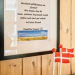 Willkommensschild an Holzwand mit dänischen Flaggen