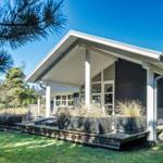 Moderne Holzhütte mit Terrasse und Garten im Wald.