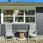 Haus mit Terrasse, zwei Stühlen und Tisch vor Fenstern mit Blick ins Innere.