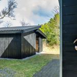 Schwarzes Holzhaus mit Dach und Tür. Holzfigur mit Häusern auf Wand.