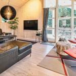 Wohnzimmer mit Ledersofa, rotem Sessel und Holzwand