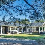 Ein modernes Haus mit Terrasse und Garten unter Bäumen.
