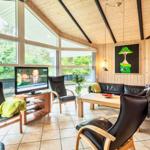 Wohnzimmer mit Holzwänden, großen Fenstern und schwarzen Ledermöbeln.