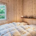 Schlafzimmer mit Holzwand, Fenster und Bett mit weißen Bettwäsche.