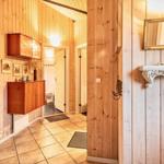 Flur mit Holzwand, Schrank, Spiegel und Bad im Hintergrund.