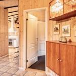 Eingangsbereich mit Holzwand, Schrank und Blick in Küche.