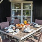 Außenbereich mit Esstisch, Stühlen und Frühstück.