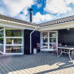 Terrasse mit Tisch, Stühlen und Glaswänden. Schwarze Fassade und Ziegeldach.
