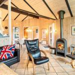 Wohnraum mit Kamin, Ledersofa und Holzwänden. Blick in Essbereich und Schlafzimmer.