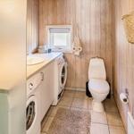 Badezimmer mit Waschmaschine, Toilette und Holzwand
