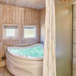 Bad mit Whirlpool, Holzwand und zwei Fenstern.