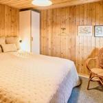 Schlafzimmer mit Holzwand, Bett, Stuhl und Fenster