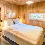 Schlafzimmer mit Holzwand, Bett und Fenster. Holzregal links. Wanddekoration.