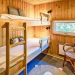 Kinderzimmer mit Doppelstockbett, Stuhl und Fenster zum Wald.