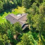 Haus mit Terrasse im Wald, grüner Rasen und Spielplatz