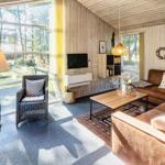 Wohnzimmer mit Holzwänden, Sofa, Couchtisch und Fernseher. Große Fenster mit Blick auf den Garten.