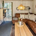 Wohnzimmer mit braunem Sofa, Holztisch und Fernseher an der Wand.