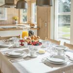 Gedeckter Esstisch mit Frühstück, Küche und Blick auf Garten.