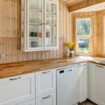 Küche mit Holzwand, weißen Schränken und Fenster zum Garten.