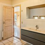 Badezimmer mit Whirlpool, Waschbecken und Spiegel. Holztür führt nach draußen.