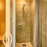 Dusche mit Duschbrause und Duschvorhang neben Sauna mit Holzbank.