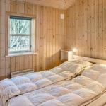Schlafzimmer mit Holzwänden, Bett und Fenster.