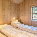 Zwei Betten in einem holzverkleideten Raum mit Fenster und Nachttisch.