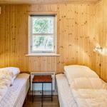 Zwei Betten in einem Holzraum mit Fenster und Tisch.