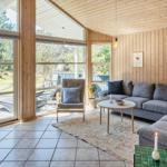 Wohnraum mit Holzwänden, Sofa, Sessel und großem Fenster zum Garten.