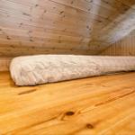 Ein Bett mit Muster liegt auf Holzboden in einem holzverkleideten Raum.