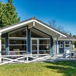 Ein blau-weißes Ferienhaus mit großem Glasbereich und Terrasse mit Gartenmöbeln.