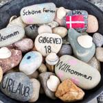 Willkommen-Schilder auf Steinen in einem Topf