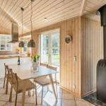 Küche mit Essbereich und Holzofen. Holzwände, Fenster und Tisch.