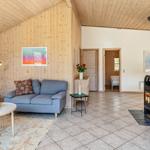 Wohnzimmer mit Holzwand, Sofa, Kamin und Blick in Schlafzimmer.