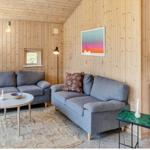 Wohnzimmer mit zwei grauen Sofas, Holzwänden und einem runden Tisch.