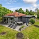 Moderne Villa mit Terrasse, Garten und Grillplatz. Umgeben von Bäumen und Grasflächen.