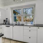Küche mit weißer Einbauküche, dunkler Arbeitsplatte und Fensterblick auf Bäume.