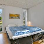 Schlafzimmer mit Doppelbett, Fenstern und Holzboden.