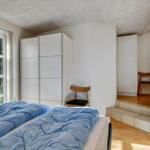 Schlafzimmer mit Bett, Kleiderschrank und Fenster zum Garten.