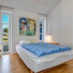 Schlafzimmer mit Bett, Wandbild und Fenstern.