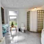 Badezimmer mit Badewanne, Dusche und Toilette. Fenster, Pflanze und Waschtisch sichtbar.
