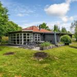 Moderne Villa mit Terrasse, Garten und Blick auf Bäume.