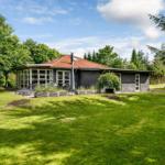 Moderne Villa mit Terrasse und Garten. Umgeben von Bäumen und Grünflächen.