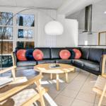 Wohnzimmer mit schwarzer Couch, Holzstühlen und großem Fenster