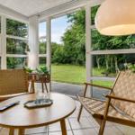 Sitzbereich mit zwei Stühlen und Tisch. Große Fenster mit Blick auf Garten.