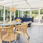 Terrasse mit Esstisch, Stühlen und Sofa. Glaswände und Decke. 