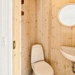 Badezimmer mit Toilette, Waschbecken und runden Spiegel an Holzwand