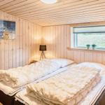 Schlafzimmer mit Holzwand, Bett und Fenster mit Blick auf Grün.