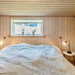 Schlafzimmer mit Holzwandverkleidung, Bett und Fenster mit Pflanzen.